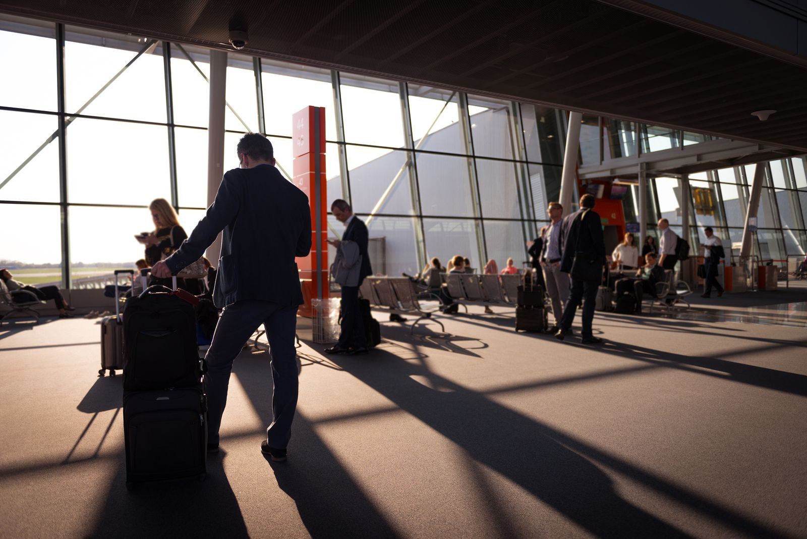 Travelers with carry-on bags in a sunlit airport terminal on the way to a river cruise